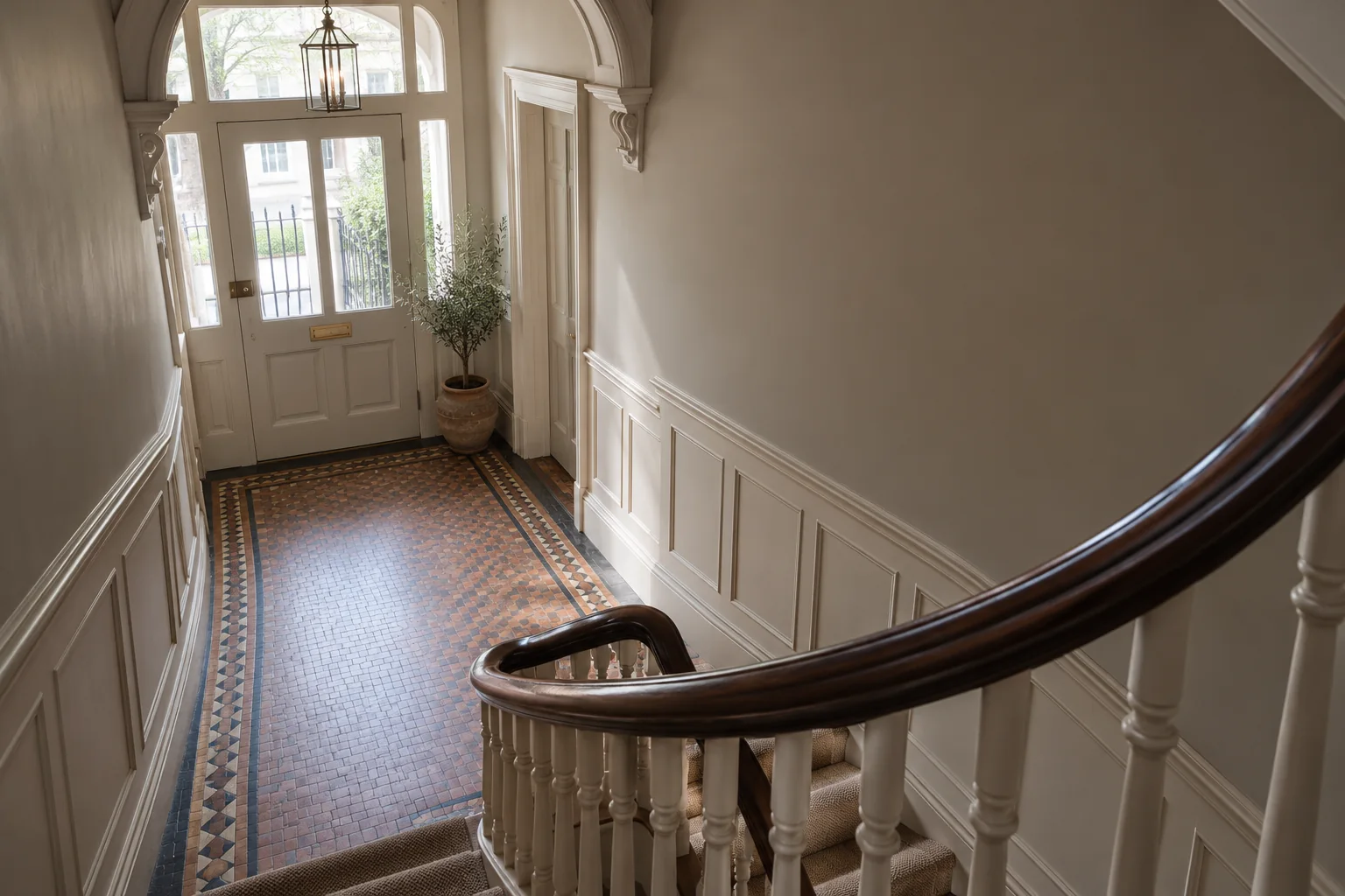 Converted-house entrance hall with a curved timber stair and painted wall panelling